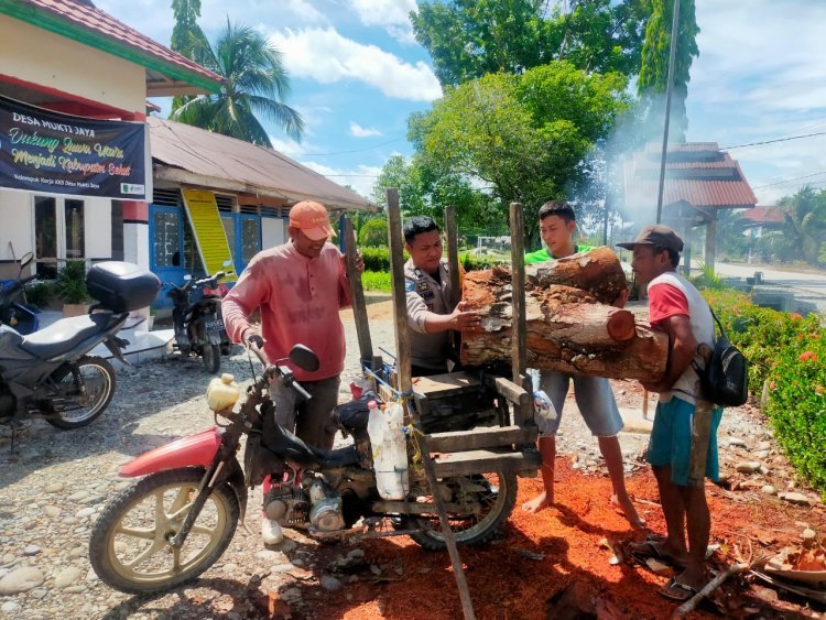 Bhabinkamtibmas Desa Mukti Jaya Polsek Baebunta Bantu Warga Bersihkan Sisa Kayu Dipinggir Jalan